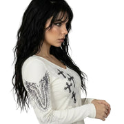 Woman wearing a white long-sleeve top with black designs on a white background